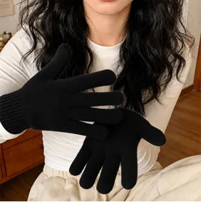 Detailed view of black knit gloves worn on hands, showing flexible fingers and cozy winter warmth.