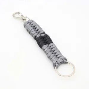 Detailed view of the woven paracord keychain, showing grey black cord texture and metal ring.