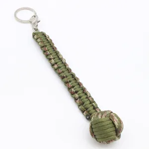 Detalle de llavero de puño de mono de paracord con cuerda de supervivencia verde y anilla.