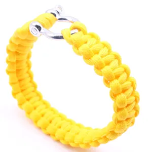 Gros plan détaillé du bracelet de survie en paracorde jaune vif 7 brins avec manille en métal.