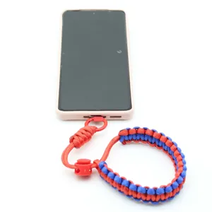 Detailopname van de duurzame rood-blauwe gevlochten paracord telefoonpolsband met verstelling.