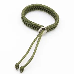 Handmade green paracord bracelet with metal adjustable buckle and dangling tail cords detail.