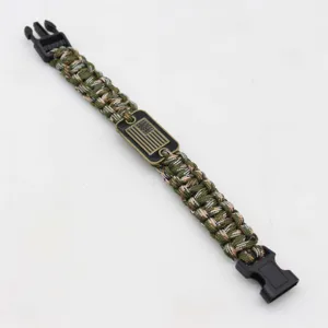 Paracord survival bracelet detail shot showing green woven cord and metal emblem clasp.