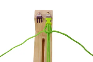 Wooden paracord jig weaving tool detail showing green cord and plastic buckle setup.