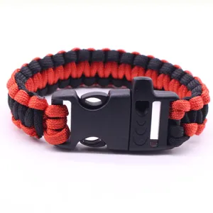Primo piano di braccialetto di sopravvivenza in paracord rosso e nero con fibbia fischietto.