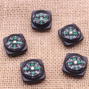 Gros plan de petits mini compas carrés noirs pour bracelets paracorde et équipement extérieur.