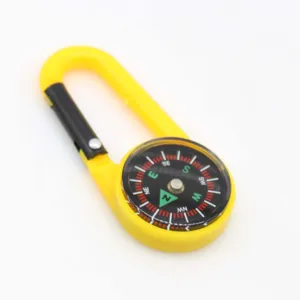 Primer plano del mosquetón amarillo portátil con brújula integrada para uso al aire libre.