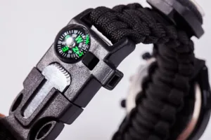Outdoor survival paracord watch buckle detail showing built-in compass and whistle design.