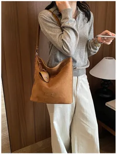 Brown suede shoulder bag detail showcasing soft texture, strap, and stylish hobo bucket design.