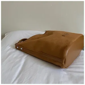 Brown suede shoulder bag detail showcasing soft matte texture and metal stud hardware.