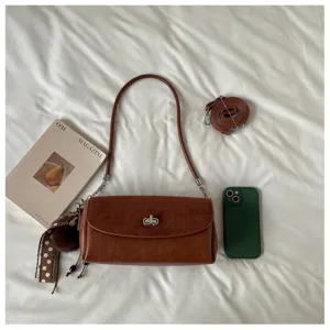 Detail shot of retro brown suede patchwork shoulder bag with metal lock and chic strap styling.