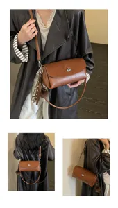 Chic retro brown leather shoulder bag with stylish turn-lock closure and cute pom-pom charm.