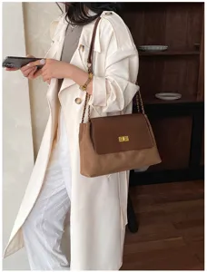 Detailed view of the stylish brown chain shoulder bag featuring metal lock worn by model.