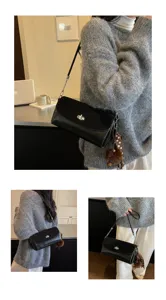 Details of black leather shoulder bag with chic lock closure, chain strap and cute charm.