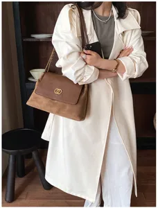 Detail shot of a stylish brown suede and leather shoulder bag with chic metal chain and clasp.