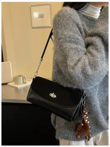 Minimalist black shoulder bag for women, stylish square handbag with metal lock and chain strap.