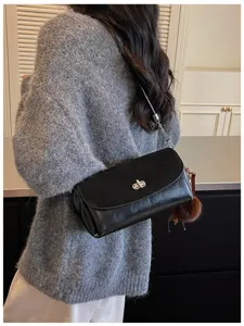 Black shoulder bag detail, suede flap and leather body with metal turn lock, chic accessory.