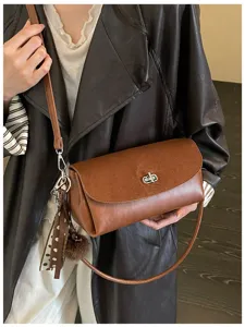 Chic stylish brown leather crossbody bag with metal lock and cute pompom charm detail.