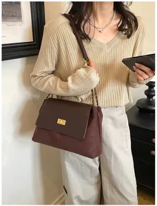 Detailed view of a stylish brown shoulder bag with a gold turn-lock and chain strap worn by model.