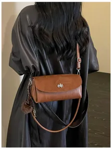 Brown leather horizontal shoulder bag detail showcasing metallic turn-lock closure and strap.
