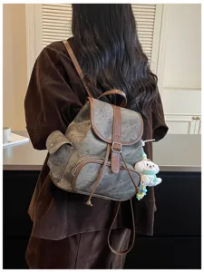 Detailed view of the casual canvas backpack with brown leather trim and cute puppy pendant.