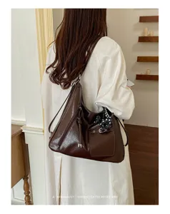 Close-up detail of the retro brown hobo shoulder bag with front pocket and stylish charm.