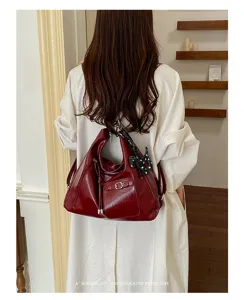 Detailed back view of a wine red vintage tote bag with decorative charm and front buckle.