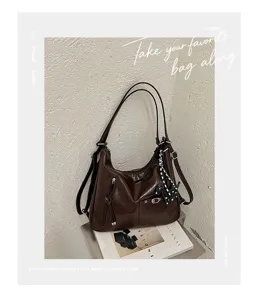 Close-up detail of vintage brown commuter hobo shoulder bag with glossy leather finish.