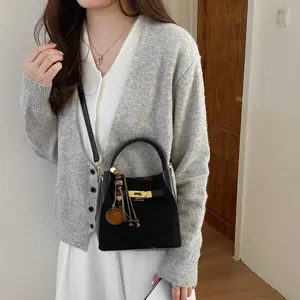 Chic black bucket bag with gold lock and tassel pendant, stylish commuter crossbody handbag.