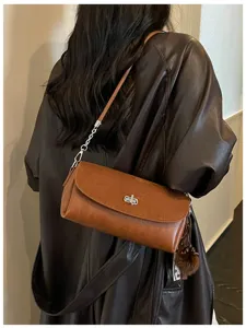 Detailed view of trendy brown shoulder bag with metal lock, chic chain strap and fluffy charm.