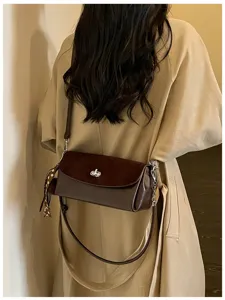 Detail shot of a chic brown suede contrast shoulder bag with metal turn-lock and scarf.