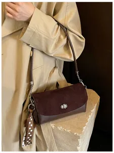 Brown suede shoulder bag detail, stylish women crossbody bag with metal lock and chic polka dot scarf.