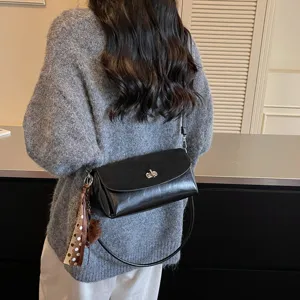 Trendy black leather shoulder bag with chic metal lock, stylish scarf and pompom charm
