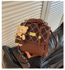 Chic brown casual backpack detail featuring quilted flap, cute bear charm and bow accent.