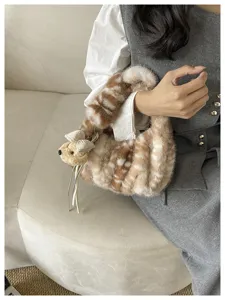 Detalle de bolso de peluche suave con estampado de ciervo y adorable colgante de osito.