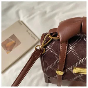 Brown suede quilted shoulder bag detail close-up showing elegant gold hardware and stitching.
