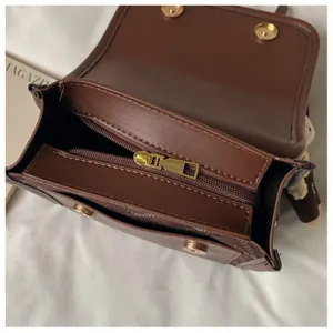 Detailed shot of a stylish brown mini leather backpack with gold zipper and secure magnetic clasps.