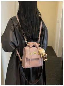 Detailed view of the pink mini backpack featuring a cute bow handle and a plush bear pendant.