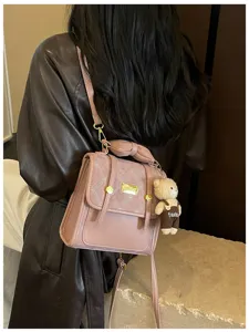 Chic pink mini backpack for women, featuring a cute bow handle and playful teddy bear.