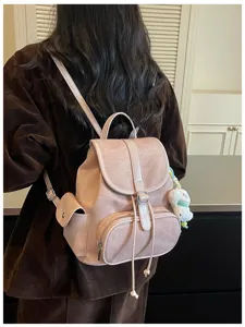 Close-up detail of casual PU leather backpack with front flap, drawstring and pendant.