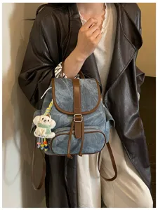 Casual denim backpack detail with brown leather trim and cute puppy charm for daily commute.