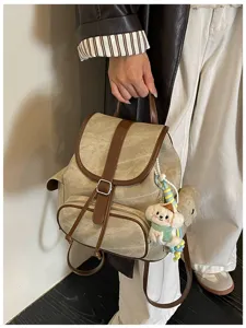 Casual canvas backpack detail view, brown leather straps, cute puppy plush pendant.