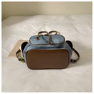 Detail view of the casual denim and brown leather backpack, showcasing fabric texture and structure.