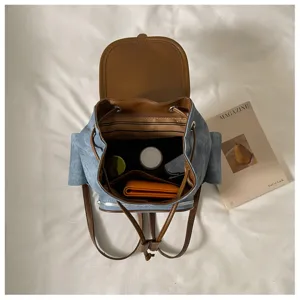 Close-up detail of casual denim backpack interior compartments and brown leather flap design.
