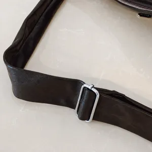 Verstelbaar schouderband detail van de minimalistische donkerbruine lederen handtas