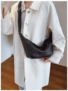 Detailweergave van de zwarte lederen halve maan schoudertas met brede riem en minimalistische stijl.