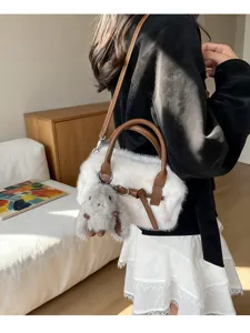 Detail view of women's plush crossbody pillow bag in white and brown with cute furry charm.