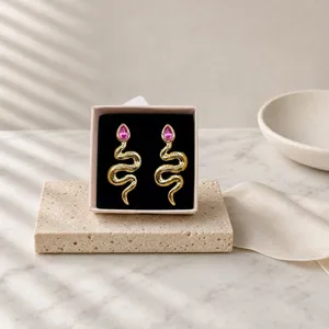 Close-up detail of vintage snake earrings with pink crystal drop in elegant gift box.