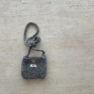 Détail du sac bandoulière gris en tricot pour téléphone, texture de laine et bouton.