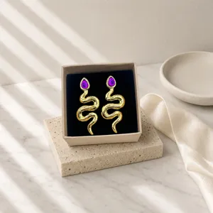 Detailed close-up view of the vintage snake-shaped earrings featuring purple gemstone inlay.